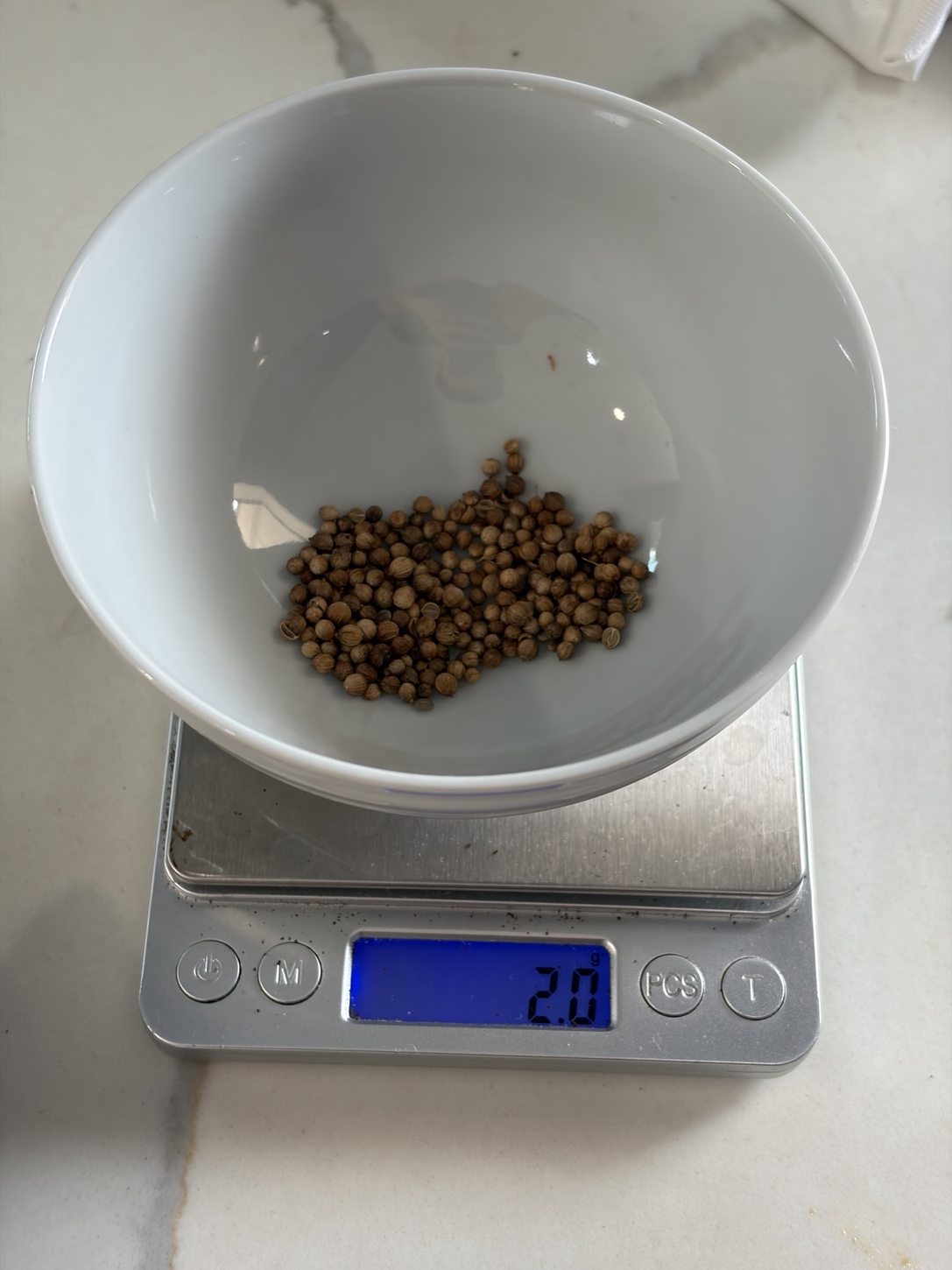 2.0 g of whole coriander seeds on a kitchen scale